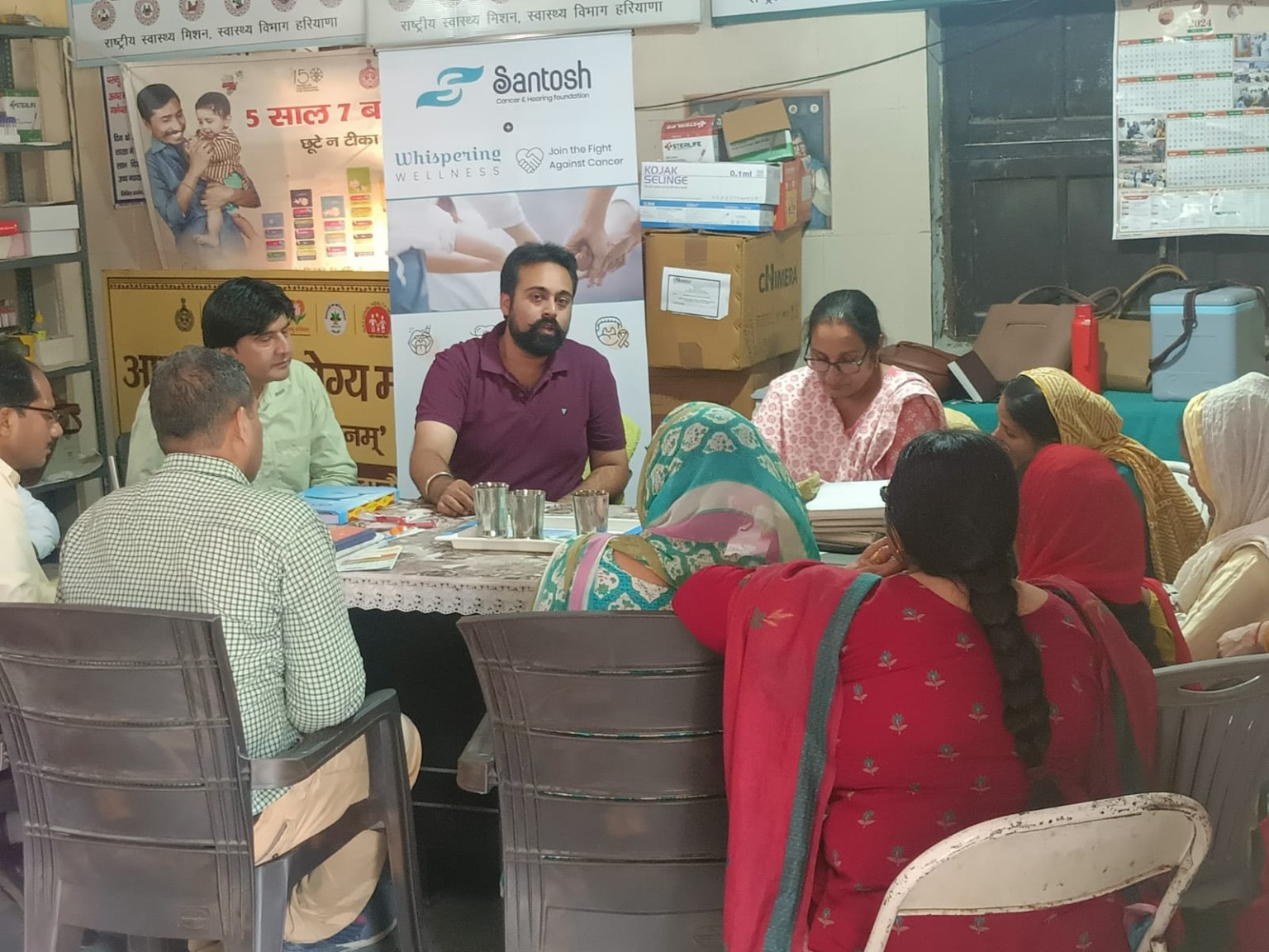 Community health meeting with a Santosh Cancer and Hearing Foundation Whispering Wellness banner